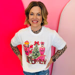 White tee with pink nutcrackers, leopard “Jolly” text, red bow, and festive Christmas tree design.