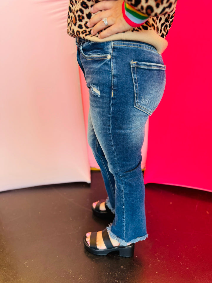 Side view of cropped denim pants showing straight-leg cut and raw hem finish