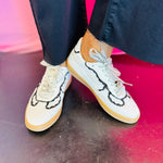 White low-top sneakers with vegan leather upper, delicate lace trim, lace-up closure, and round toe.