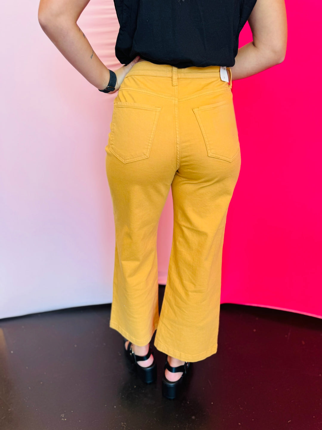 Rear view of gold crop wide-leg jeans with high-rise waist and two back patch pockets.