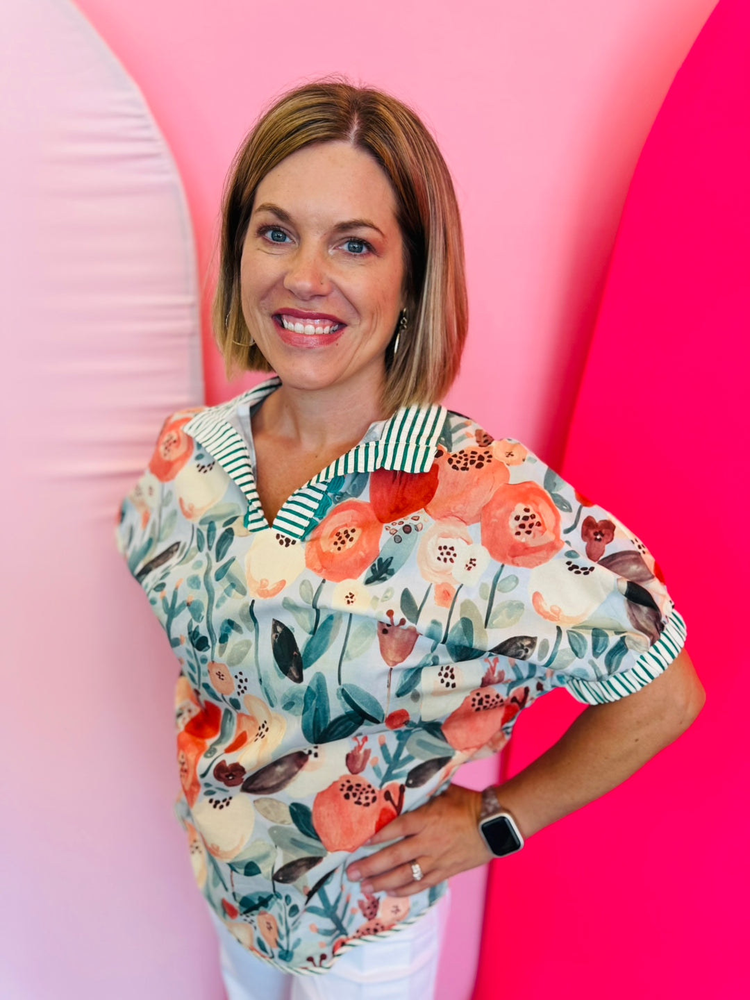 Teal floral mock neck top with coral and peach blooms, striped split neckline with decorative trim, and relaxed short puff sleeves.