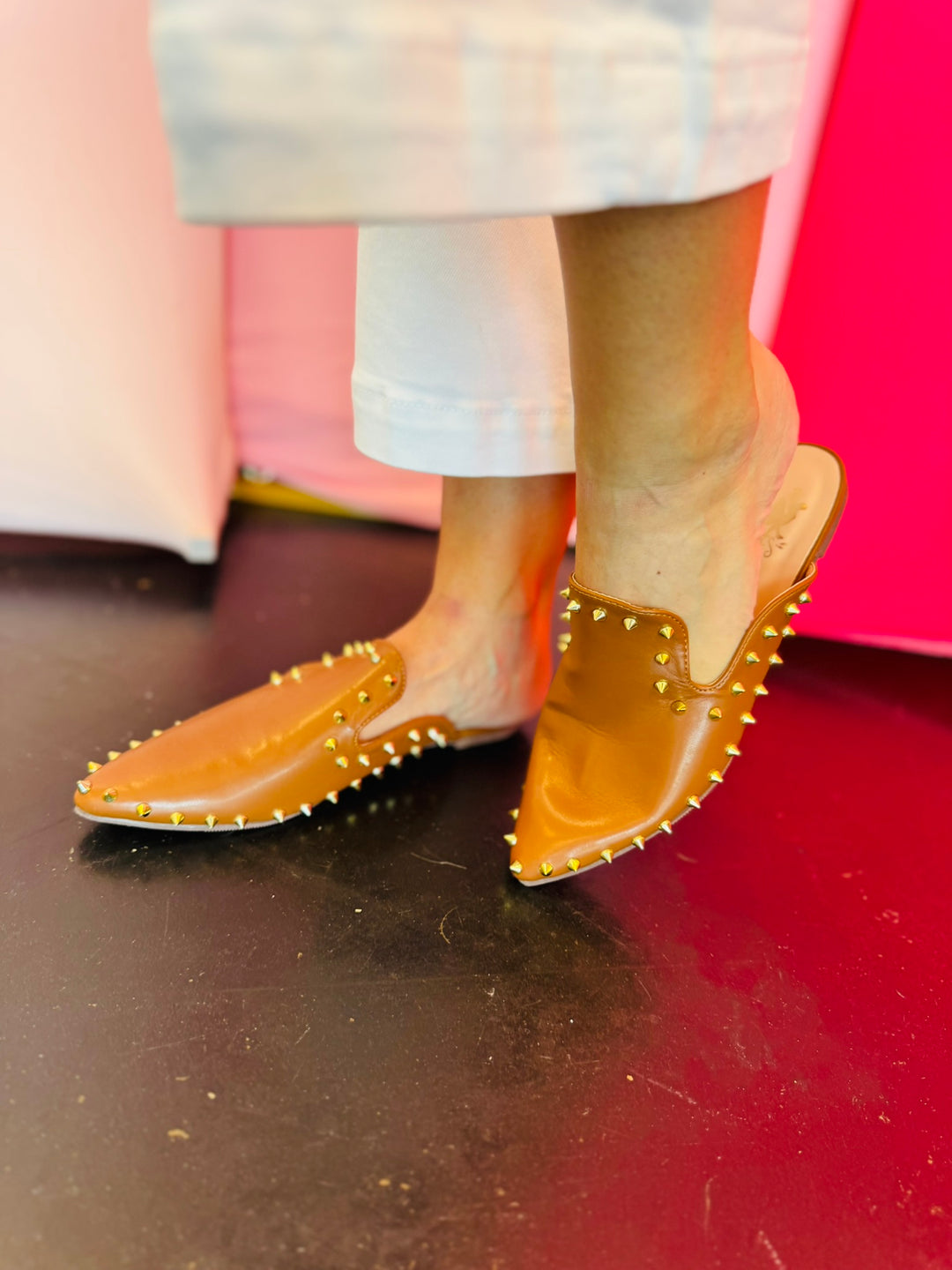Camel-colored slide sandals with sleek silhouette and spikey stud embellishments along the edge