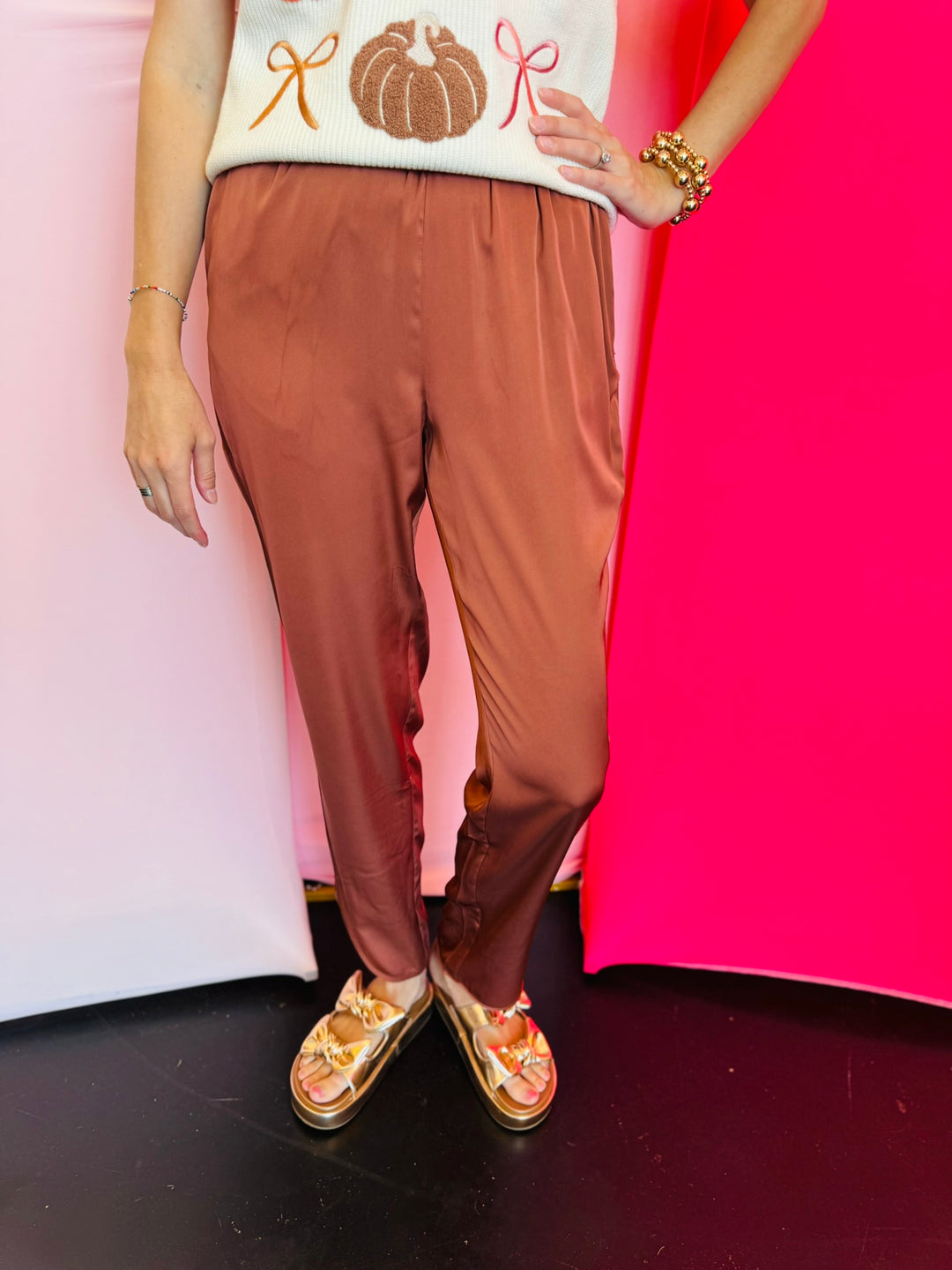 Cinnamon satin jogger-style pants with smocked elastic waistband, relaxed fit, and side pockets.