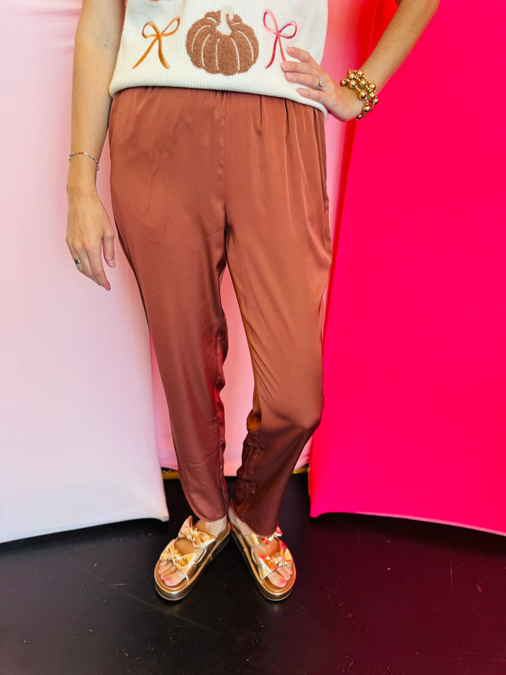 Cinnamon satin jogger-style pants with smocked elastic waistband, relaxed fit, and side pockets.