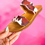 Brown cow print Corkys Wishy Washy sandals featuring playful crisscross straps, cushioned footbed, and a comfortable, modern slip-on design perfect for casual summer wear.