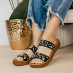 Black embellished double-strap slip-on sandals featuring a cushioned sole and a trendy, versatile design. The straps are adorned with eye-catching details, offering both comfort and style in a sleek silhouette.