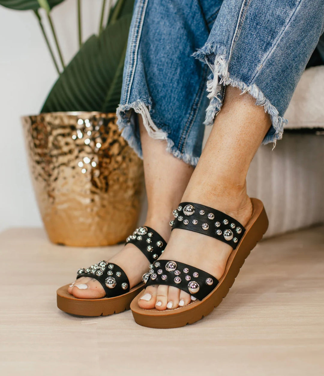 Black embellished double-strap slip-on sandals featuring a cushioned sole and a trendy, versatile design. The straps are adorned with eye-catching details, offering both comfort and style in a sleek silhouette.