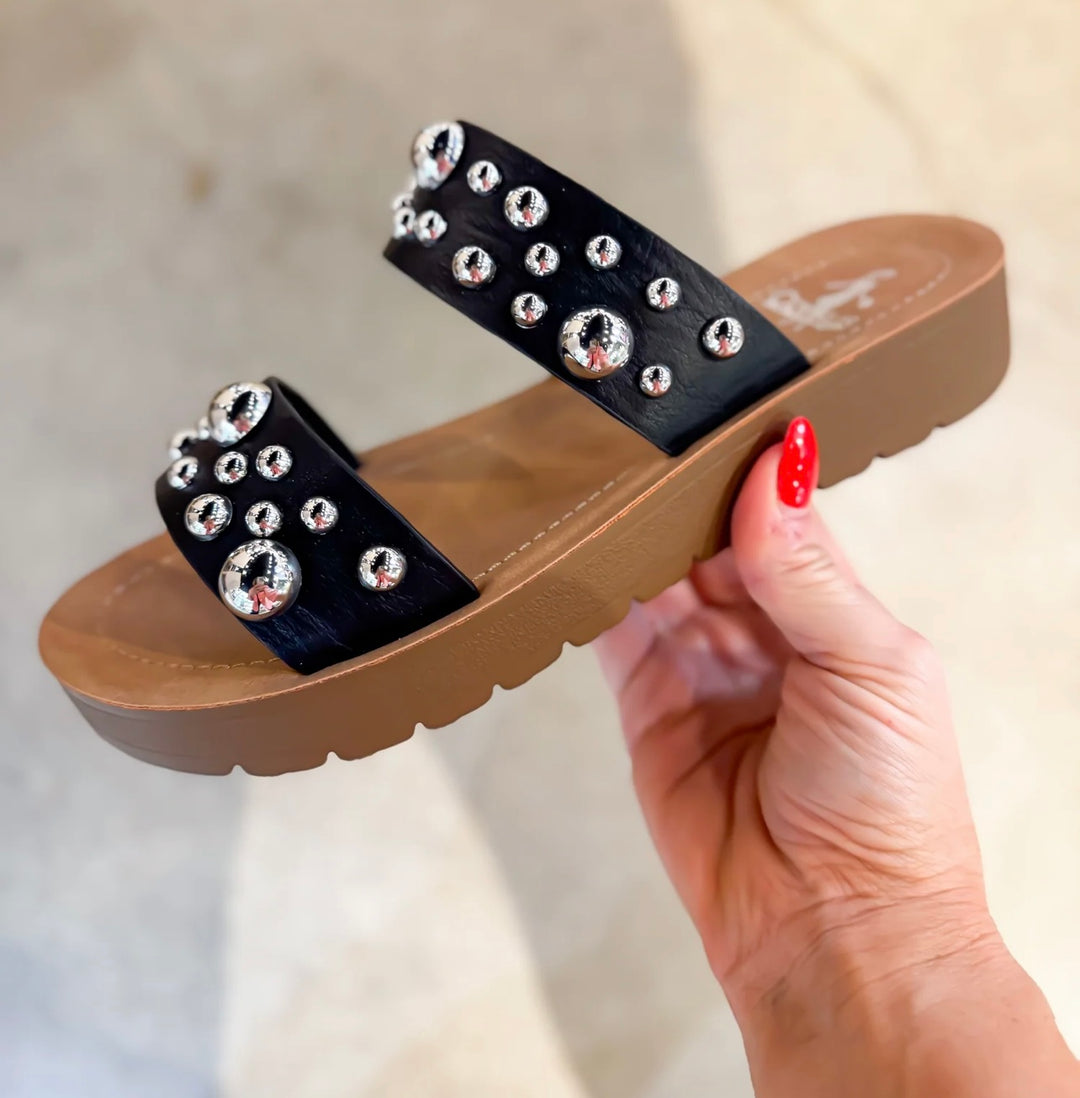 Black embellished double-strap slip-on sandals featuring a cushioned sole and a trendy, versatile design. The straps are adorned with eye-catching details, offering both comfort and style in a sleek silhouette.