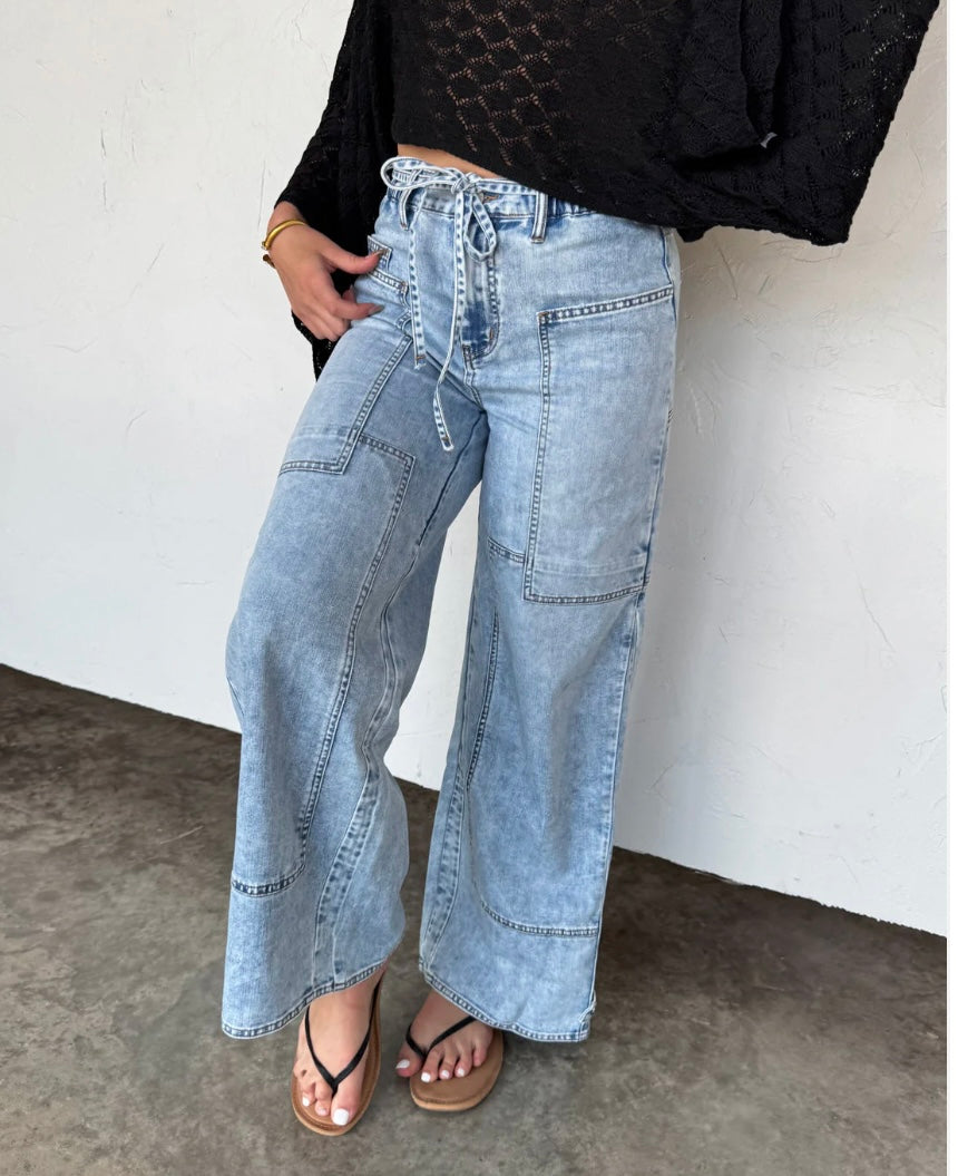 Light denim boho-inspired jeans with tie waist and front panel pockets, ideal for summer styling.