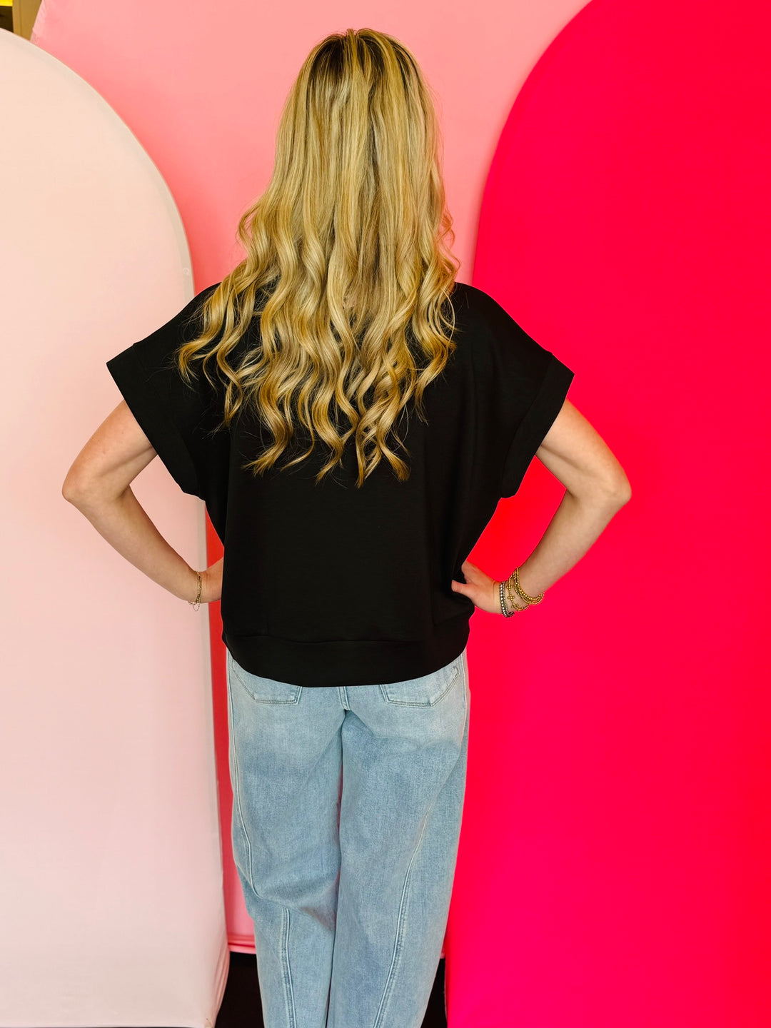Black scuba high neck top with half zip, displayed folded and styled with denim for a casual-chic look.
