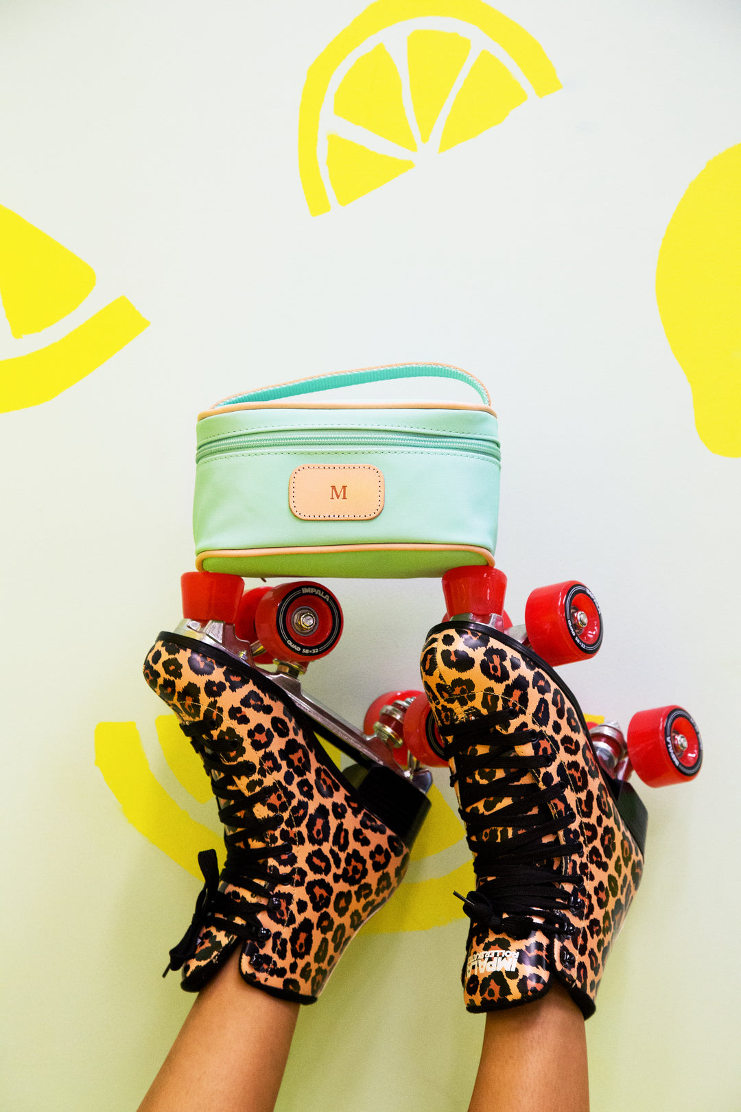 A mint green Mini Makeup case with natural leather trim and a monogrammed "M" patch.