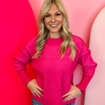 Hot pink two-tone sweater with exposed seams, hi-low hem, and contrasting ribbed trim.