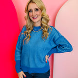 Ocean blue two-tone sweater with exposed seams, hi-low hem, and contrasting ribbed trim.