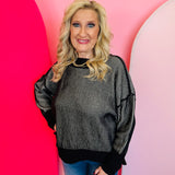 A relaxed-fit, black and white striped sweater with long sleeves. The sweater has visible exposed seams, a hi-low hemline, and side slits.