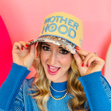 Motherhood trucker hat with tan crown, corduroy details, leopard bill, and “raising wild things” embroidery.