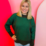 Dark olive two-tone sweater with exposed seams, hi-low hem, and contrasting ribbed trim.