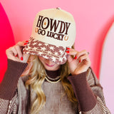 Cream snapback hat with brown “Howdy Go Lucky” embroidery and star accents on the bill.