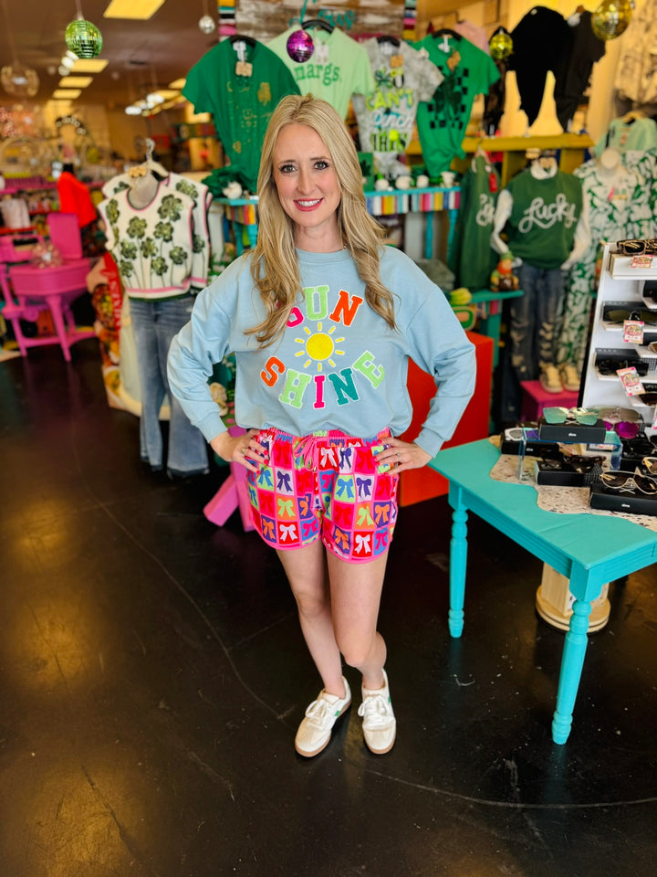 Mid-rise bow print shorts with tie waist drawstring, side pockets, and relaxed fit.