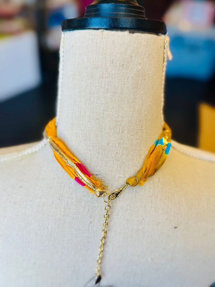 Gold print scarf necklace featuring a delicate gold butterfly charm; a whimsical and stylish accessory perfect for adding elegance and playful charm to any outfit.