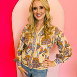 A v-neck jacquard knit cardigan. The cardigan has a detailed floral pattern in warm taupe, brown, and cream tones, with a button front closure.