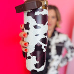 Chocolate cow print insulated tumbler with handle, screw-on lid, and car cup holder–friendly base.