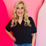 Black collared V-neck airflow top with short sleeves and a smooth, lightweight drape.