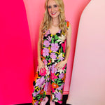 Black floral jumpsuit with shoulder ties, scalloped wide-leg hems, and vibrant multicolor blooms.
