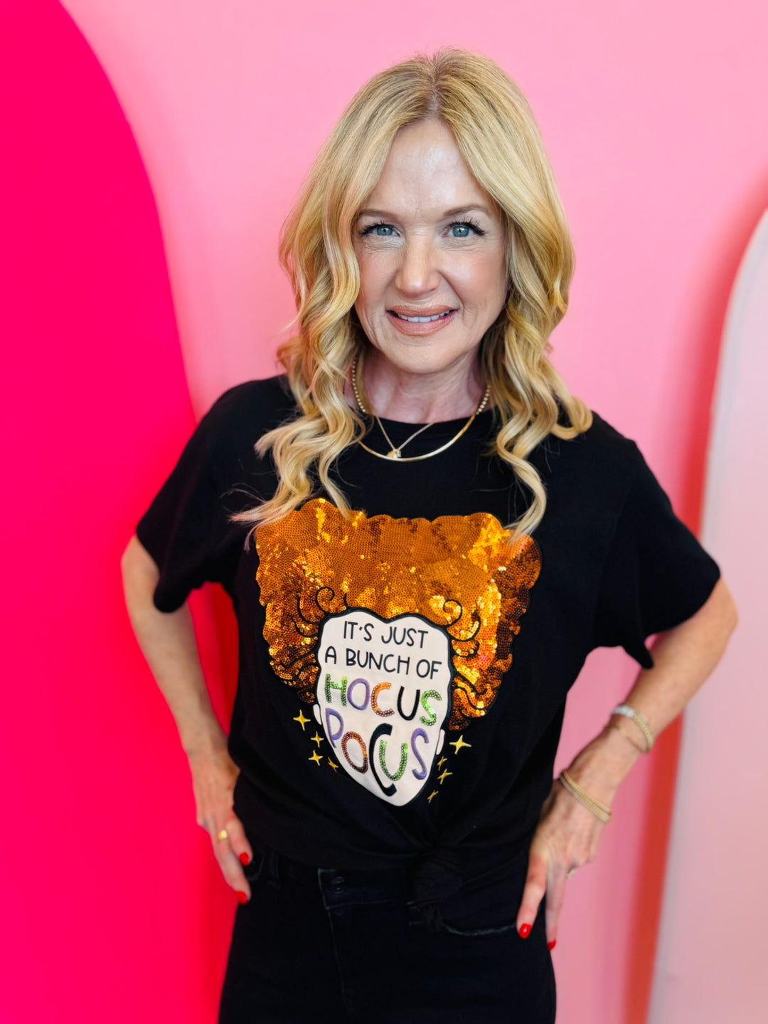 A black crewneck t-shirt featuring a glittery orange witch hat graphic. Below the hat, the text reads, "It's Just a Bunch of Hocus Pocus" in a stylized font.