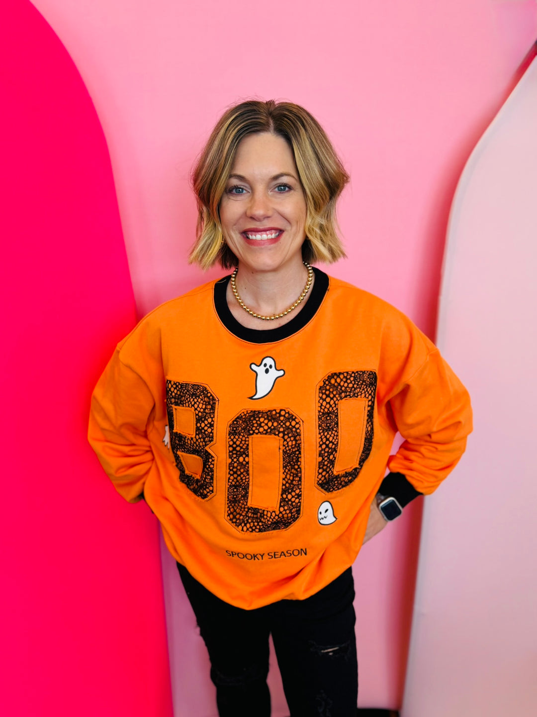 Orange sweatshirt with black neckline, cuff, and hem and  'BOO' and ghost design