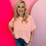 Coral ribbed striped top with exposed seams, cuffed sleeves, and flattering high-low hem.