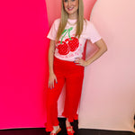 Pink tee with bold cherry graphic and cheerful “Cherryin’ up the sweet life” message.
