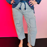 Navy striped twill barrel pants with rope tie, decorative pockets, and relaxed cotton fit.