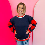 Navy pullover with red heart elbow patches, raw cut edges, and contrast neckline and hem.