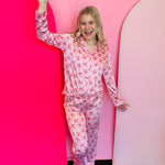 two piece button up pink satin pajama set with long-sleeve button-up top and pants and small red candy canes and bows.