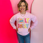 Pink Holly Jolly sweatshirt with rhinestone lettering, ornaments, and snowflake accents.