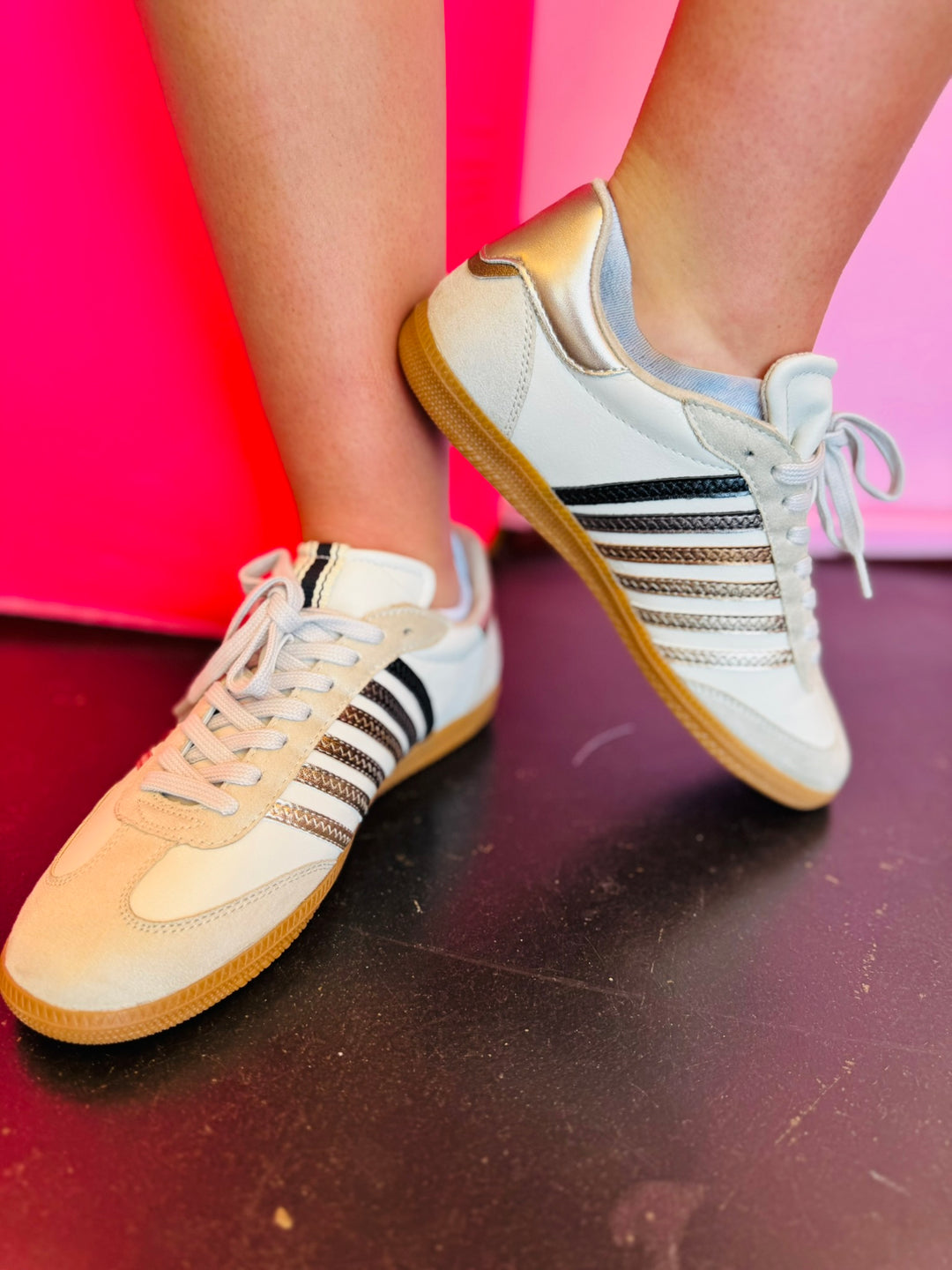 Off white sneakers with metallic stripes in black, charcoal, bronze, and silver with rounded toe and gold heel tap.