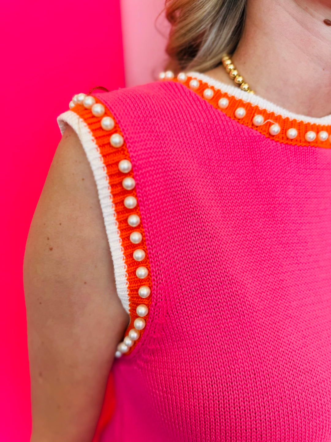 Zoomed-in image focusing on the pearl embellishments and orange/white striped neckline and sleeve hemline.