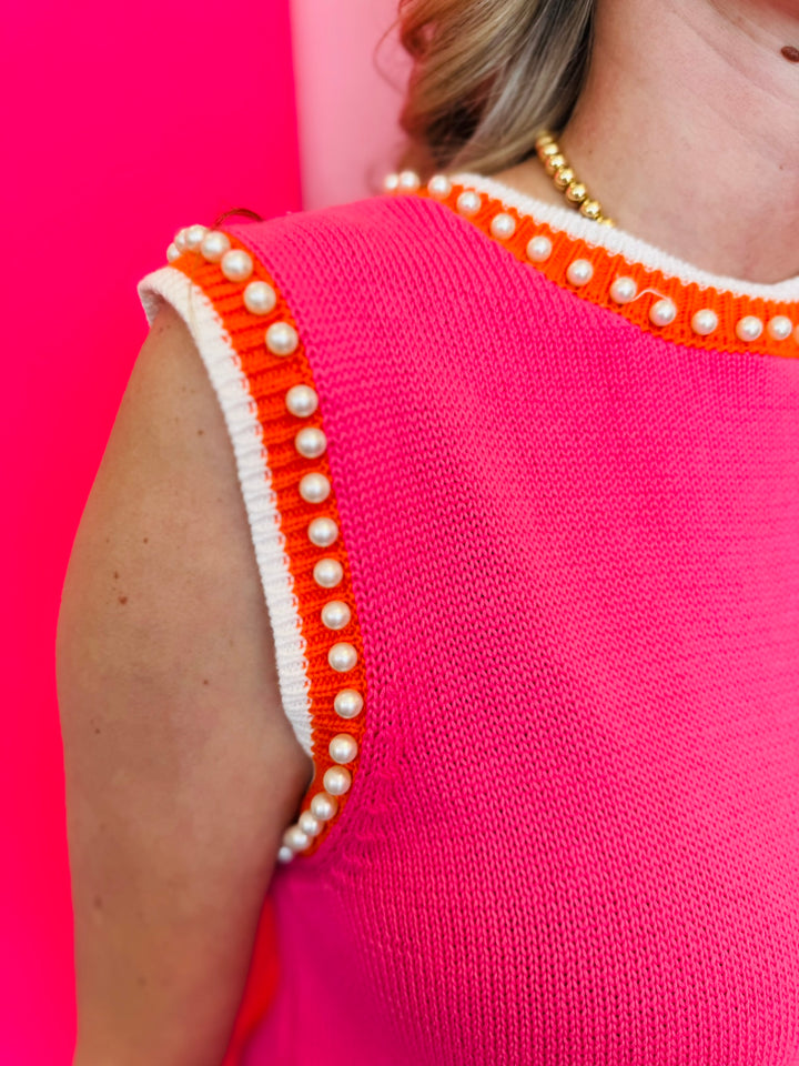 Zoomed-in image focusing on the pearl embellishments and orange/white striped neckline and sleeve hemline.