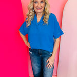 Ocean blue collared V-neck airflow top with short sleeves and a lightweight, breezy drape.