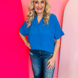 Ocean blue collared V-neck airflow top with short sleeves and a lightweight, breezy drape.