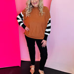 Camel mock neck sweater with bold black-and-white striped sleeves and relaxed high-low fit.