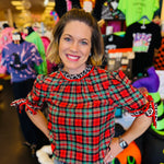 Red, green, and black plaid top with leopard accents, ruffled sleeves, and mock neckline.