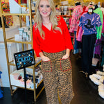 Wide-leg leopard print pants with red stitch pocket detail and elastic waistband.