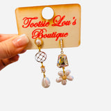Asymmetrical gold earrings with pearl drops, iridescent stones, and floral pearl cluster design