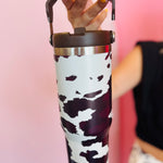 Chocolate cow print insulated tumbler with handle, screw-on lid, and car cup holder–friendly base.