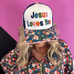 White and navy Jesus Loves You hat with colorful embroidery, floral bill, and cross detail.