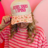 Floral bill canvas cap with pink embroidered “Jesus Saves I Spend” phrase and adjustable strap.