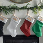 Elegant Jon Hart coated canvas holiday stocking with leather trim hanging by the fireplace
