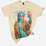Cream Lady Liberty graphic tee with pink sunglasses, leopard coat, and rhinestone details.