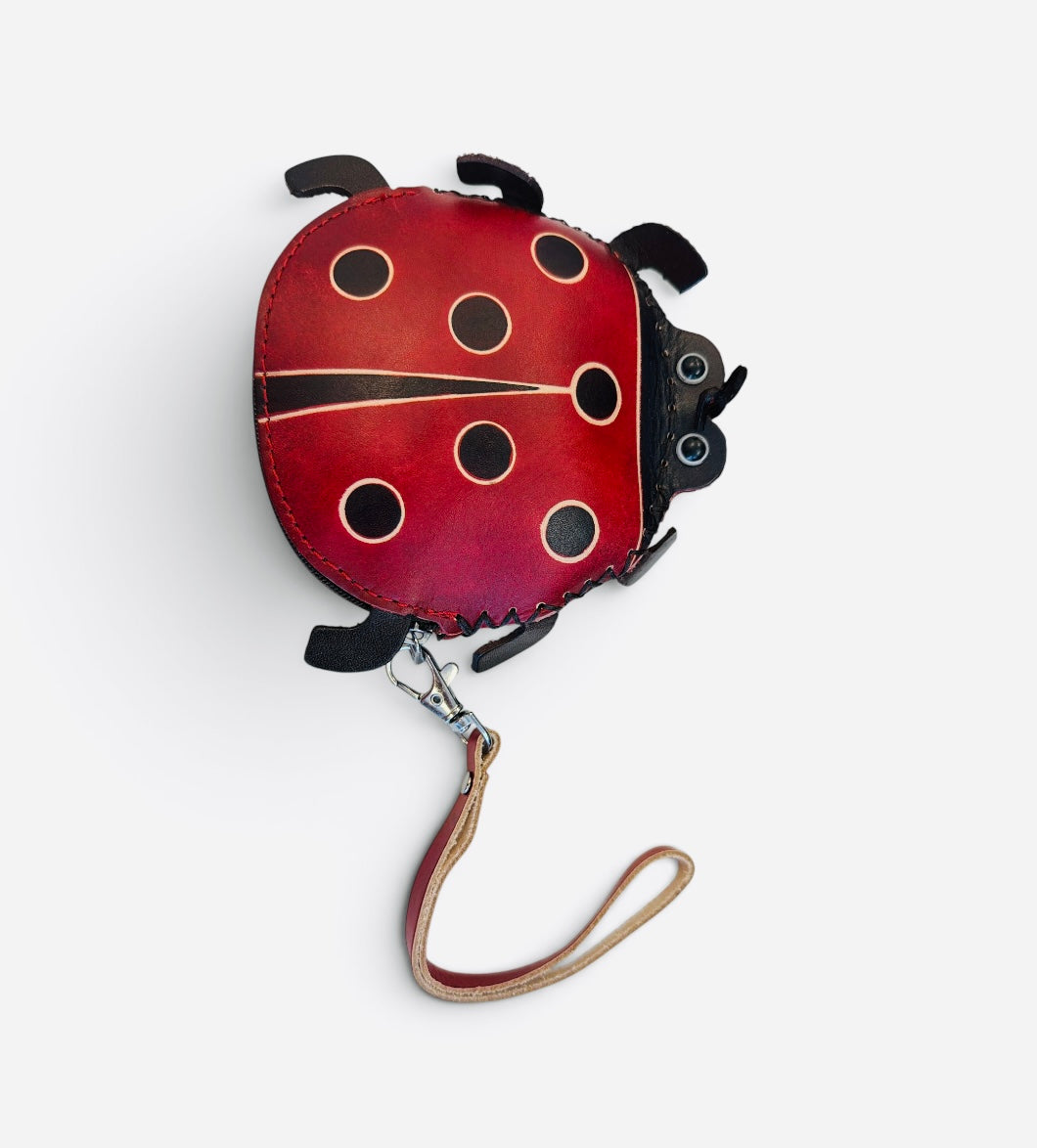 Red ladybug coin purse with black spots, zipper closure, and detachable wristlet strap.